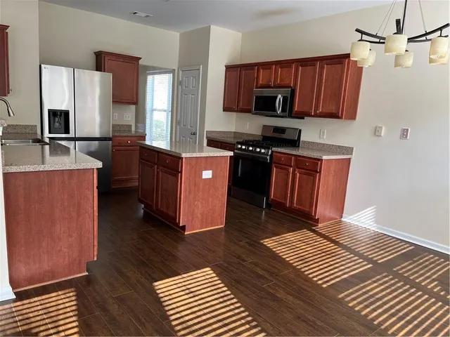 a kitchen with stainless steel appliances granite countertop a stove top oven a sink dishwasher and microwave with wooden floor