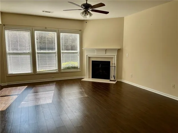 an empty room with wooden floor fireplace and windows