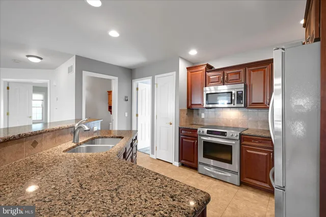 a kitchen with stainless steel appliances granite countertop a stove top oven a sink and a refrigerator