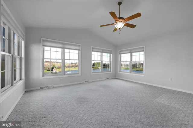 a view of an empty room with window and a ceiling fan