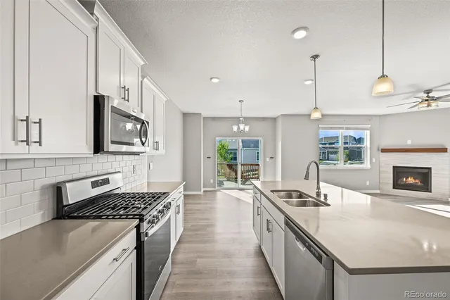 a large kitchen with stainless steel appliances granite countertop a stove a sink and a white cabinets