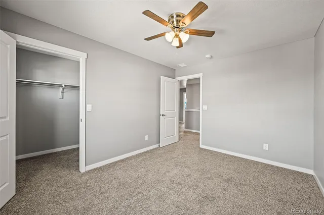 an empty room with closet and a ceiling fan