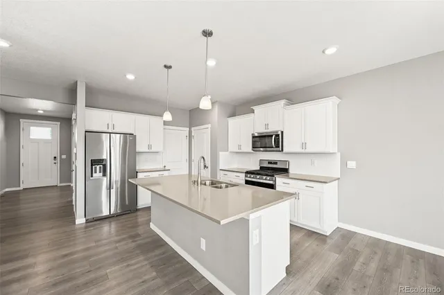 a kitchen with stainless steel appliances granite countertop a refrigerator a stove oven a sink dishwasher and white cabinets with wooden floor