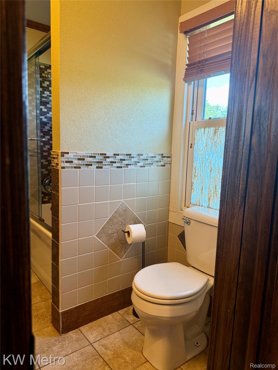 5982 South Mission Road Mount Pleasant, MI 48858 - Photo 10 of 32 Full bathroom with enclosed tub / shower combo, tile walls, a textured wall, wainscoting, and tile patterned flooring