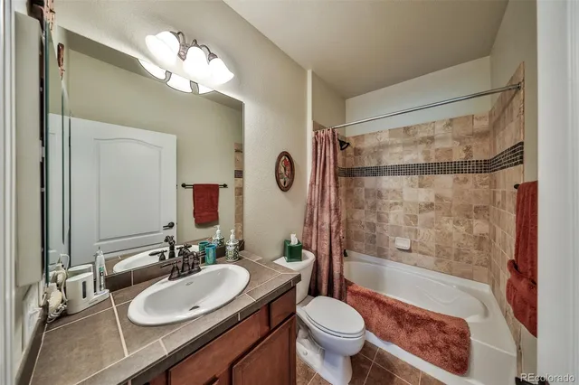 a bathroom with a sink a toilet a mirror a bathtub and shower