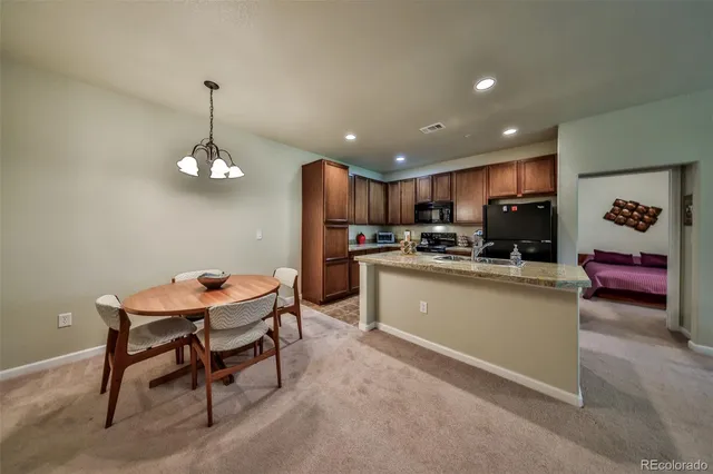 a kitchen with stainless steel appliances kitchen island granite countertop a refrigerator a stove a sink a dining table and chairs with wooden floor