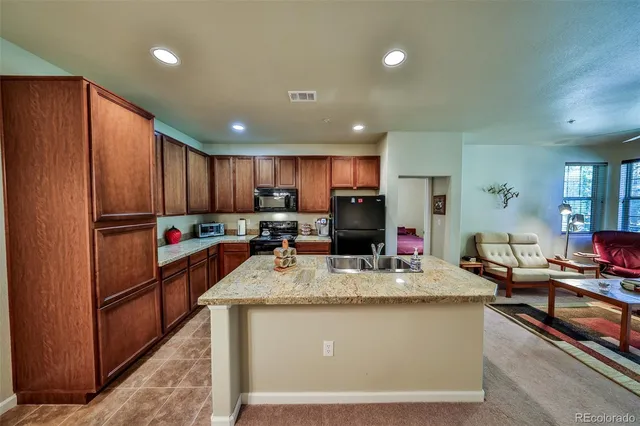 a kitchen with sink a refrigerator and chairs