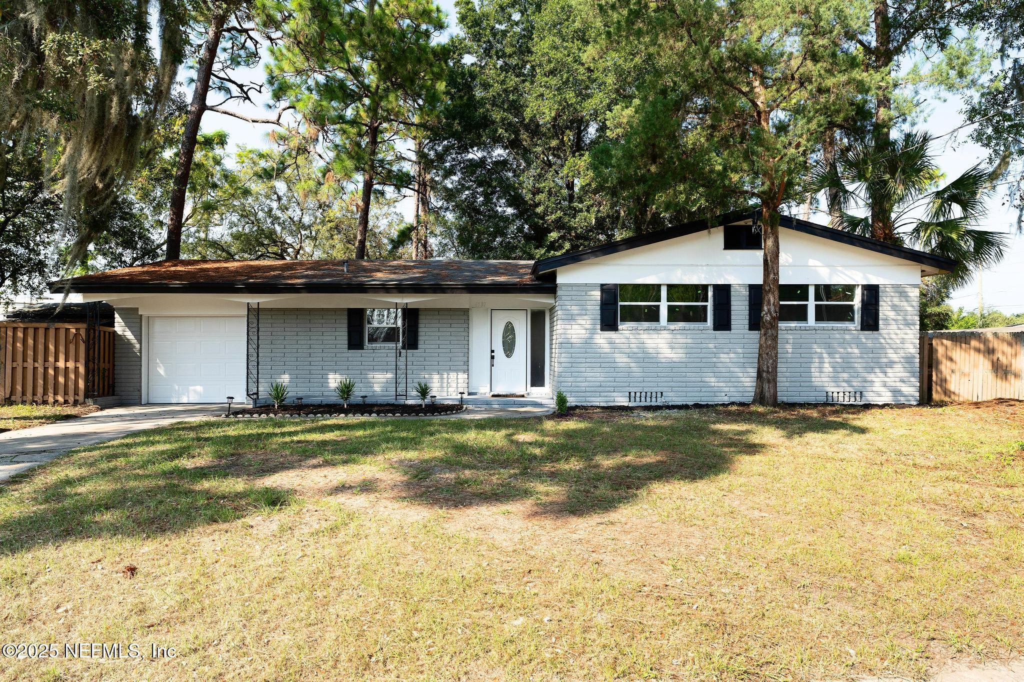 6537 Simca Drive Jacksonville, FL 32277 - Photo 2 of 25 a front view of a house with a garden