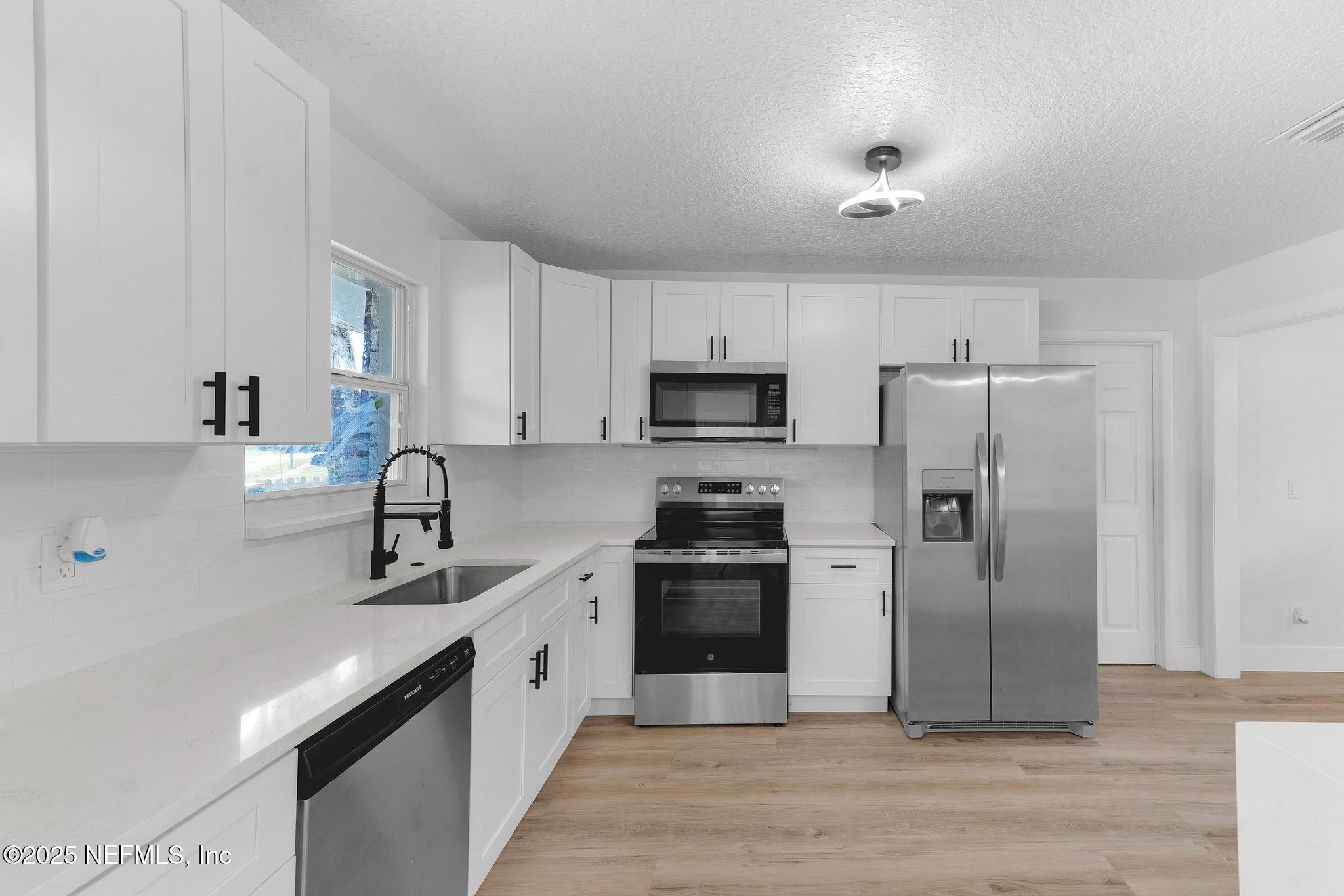 6537 Simca Drive Jacksonville, FL 32277 - Photo 6 of 25 a kitchen with stainless steel appliances a refrigerator sink and white cabinets