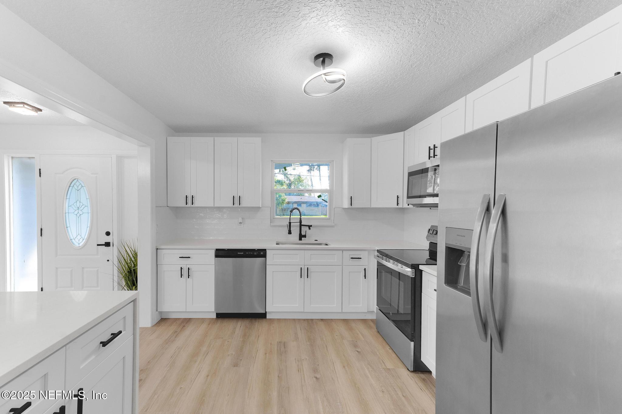 6537 Simca Drive Jacksonville, FL 32277 - Photo 7 of 25 a kitchen with a sink stainless steel appliances and cabinets