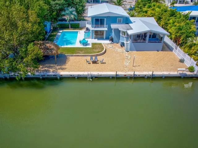 an aerial view of a house with swimming pool a yard and a large tree