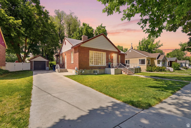 Brick residence featuring a concrete driveway, detached garage, and mature landscaping