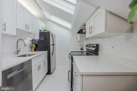 a kitchen with stainless steel appliances a sink dishwasher a refrigerator and cabinets