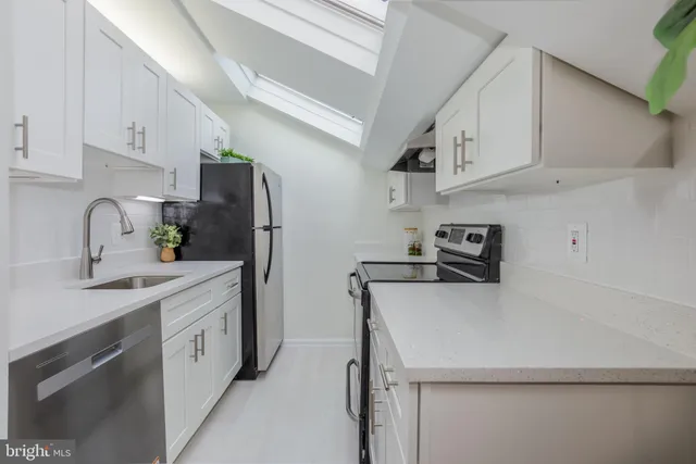 a kitchen with stainless steel appliances a sink dishwasher a refrigerator and cabinets