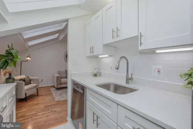a kitchen with white cabinets a sink and dishwasher
