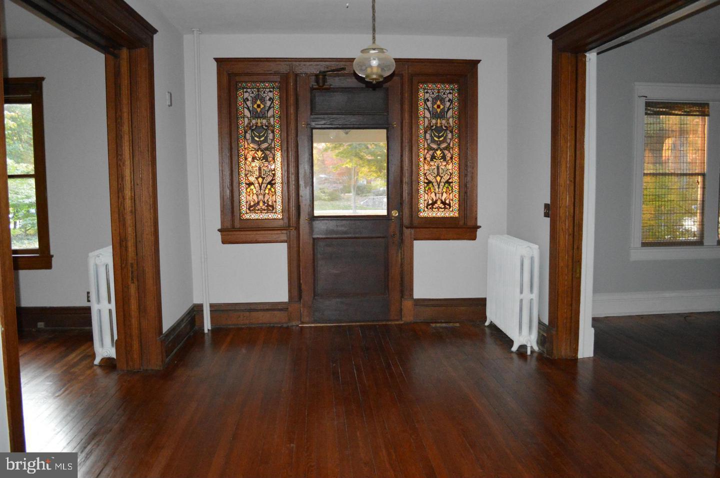 5713 Roland Avenue Baltimore, MD 21210 - Photo 15 of 29 an empty room with wooden floor chandelier and windows