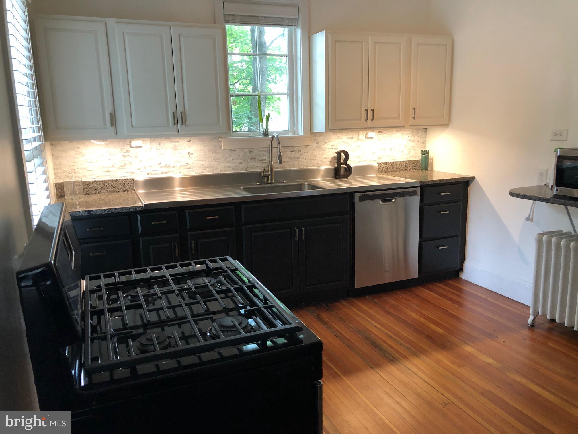 5713 Roland Avenue Baltimore, MD 21210 - Photo 2 of 29 a kitchen with granite countertop a stove a sink dishwasher and cabinets