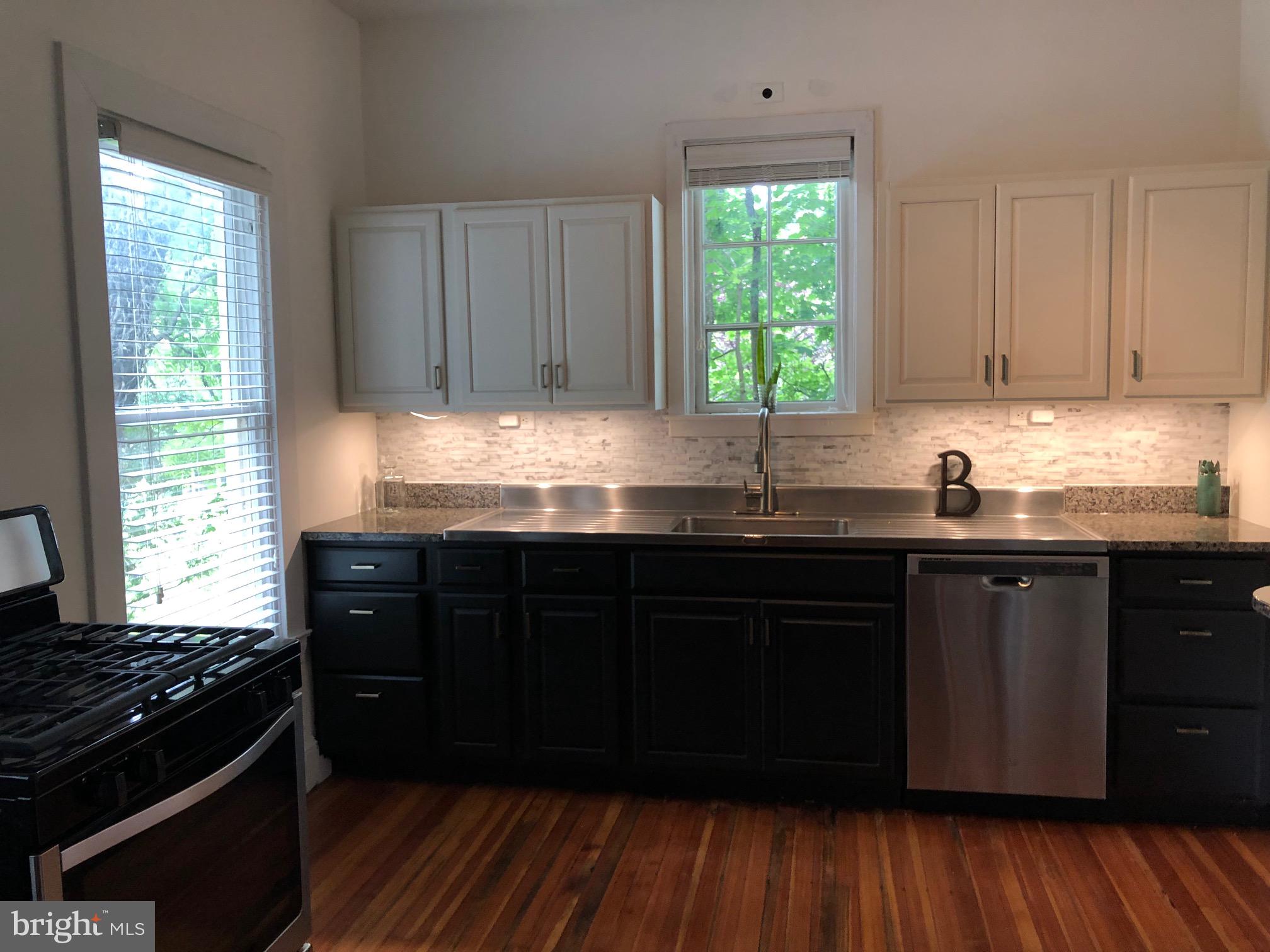 5713 Roland Avenue Baltimore, MD 21210 - Photo 3 of 29 a kitchen with granite countertop wooden cabinets a sink and a window