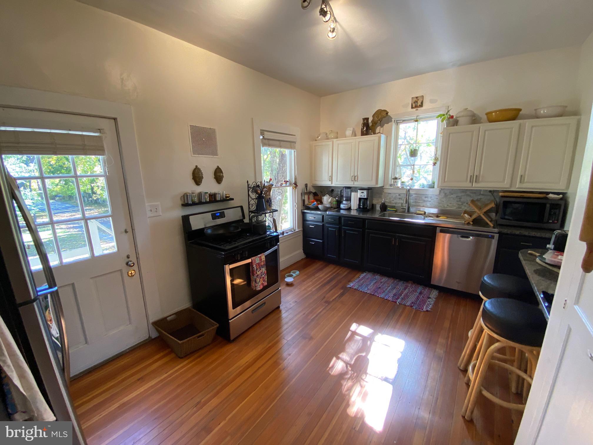 5713 Roland Avenue Baltimore, MD 21210 - Photo 6 of 29 a kitchen with wooden floors and black appliances