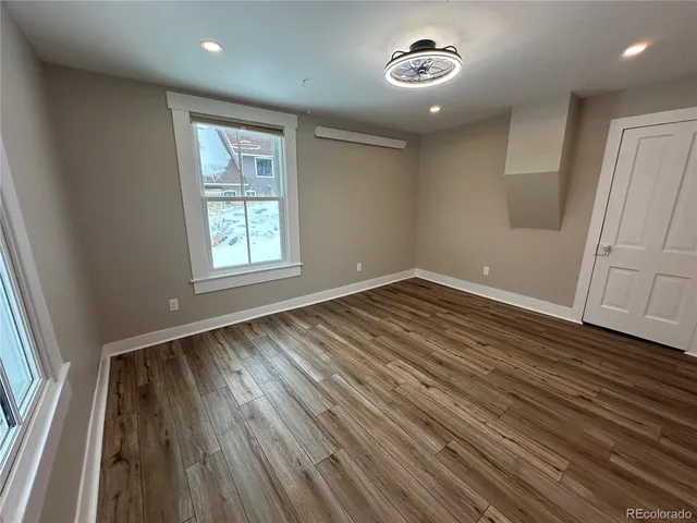 an empty room with wooden floor and windows