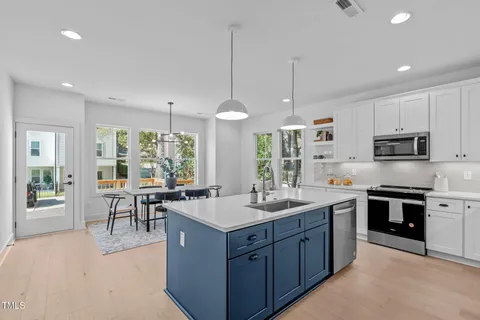 a kitchen with kitchen island granite countertop a sink stove and cabinets