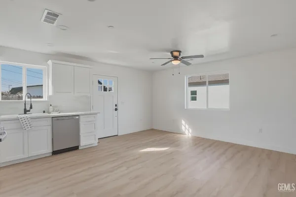 a view of a kitchen with a sink dishwasher a refrigerator and cabinets with wooden floor
