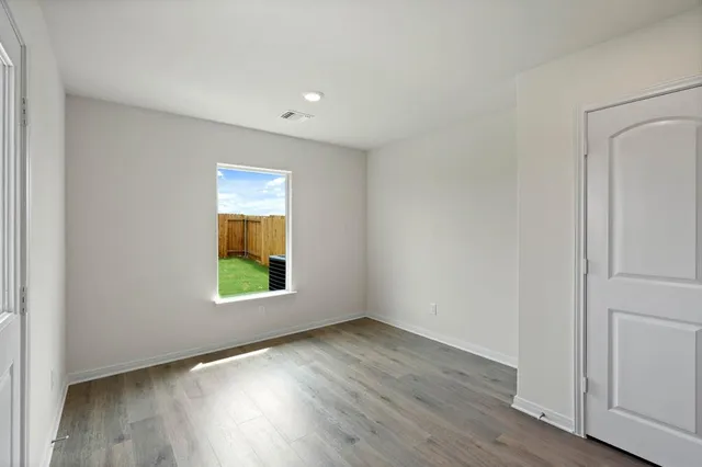 a view of an empty room with wooden floor and a window