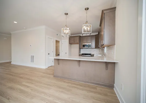 a kitchen with stainless steel appliances granite countertop a sink a stove and a wooden floors