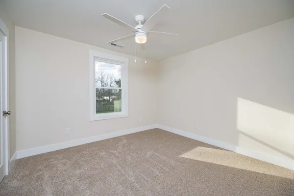 an empty room with a window and a fan