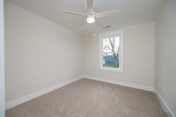 an empty room with windows and fan