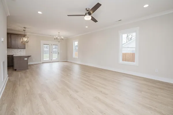 an empty room with wooden floor and windows