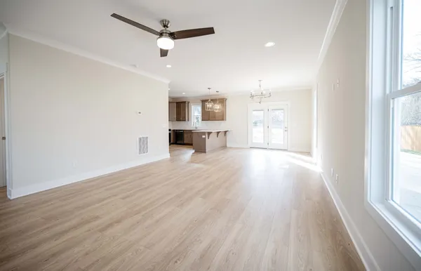 a view of a kitchen and an empty room with wooden floor and a window