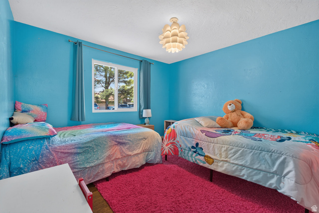 1690 Maplewood Way St. George, UT 84790 - Photo 12 of 17 Bright dual-bedroom space with vibrant turquoise walls, large window with natural light, wood-finish flooring, and a decorative pendant ceiling fixture