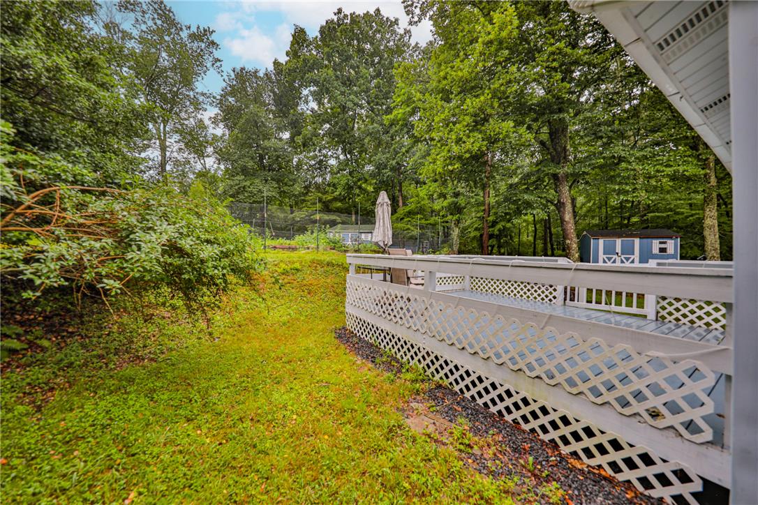 5599 Minks Pond Road Bushkill, PA 18324 - Photo 44 of 64 A spacious backyard with a private deck, abundant greenery, and mature trees offers a serene escape.