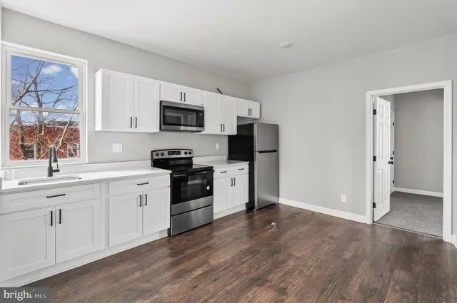 a kitchen with granite countertop a refrigerator stove top oven and sink