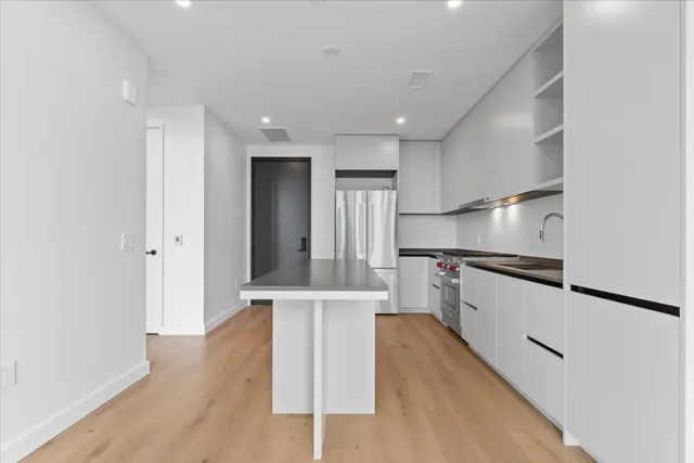 a kitchen with stainless steel appliances granite countertop a refrigerator a stove and a sink