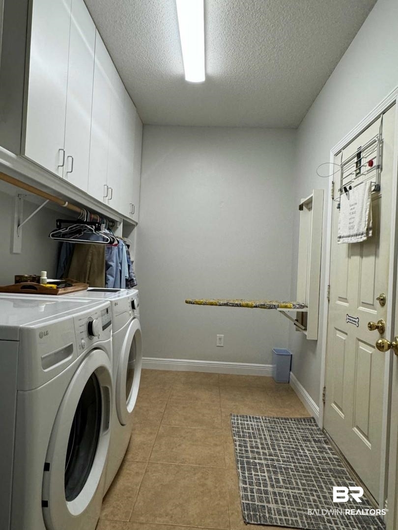 31163 Woodland Way Daphne, AL 36527 - Photo 27 of 44 Clothes washing area with a textured ceiling, washing machine and dryer, light tile patterned floors, and cabinets