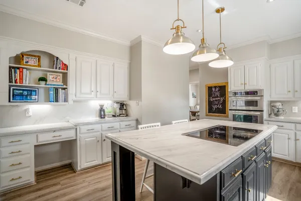 a kitchen that has a sink a kitchen island a stove and a wooden floor