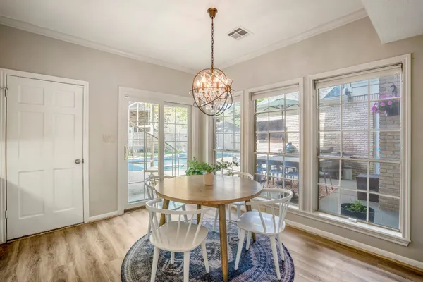 a dining room with wooden floor a chandelier a glass table and chairs