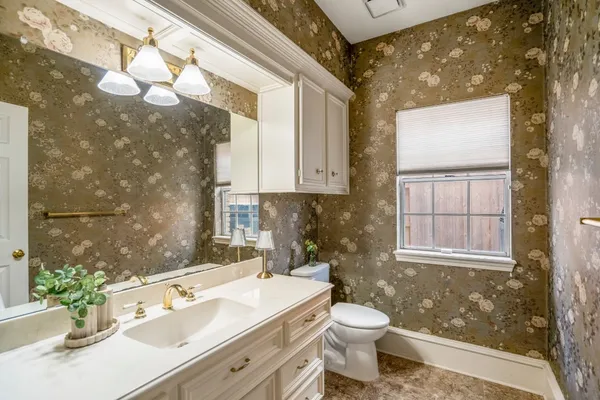 a bathroom with a sink vanity granite toilet and a mirror