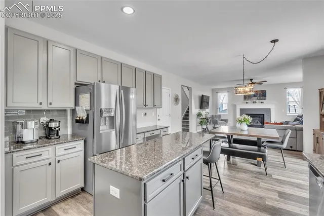 a kitchen with kitchen island granite countertop a table chairs refrigerator and cabinets