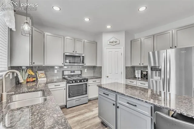 a kitchen with stainless steel appliances granite countertop a stove a sink and a refrigerator