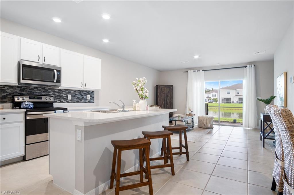 15070 Wildflower Circle Naples, FL 34119 - Photo 2 of 22 a kitchen with a stove a sink a microwave a dining table and chairs