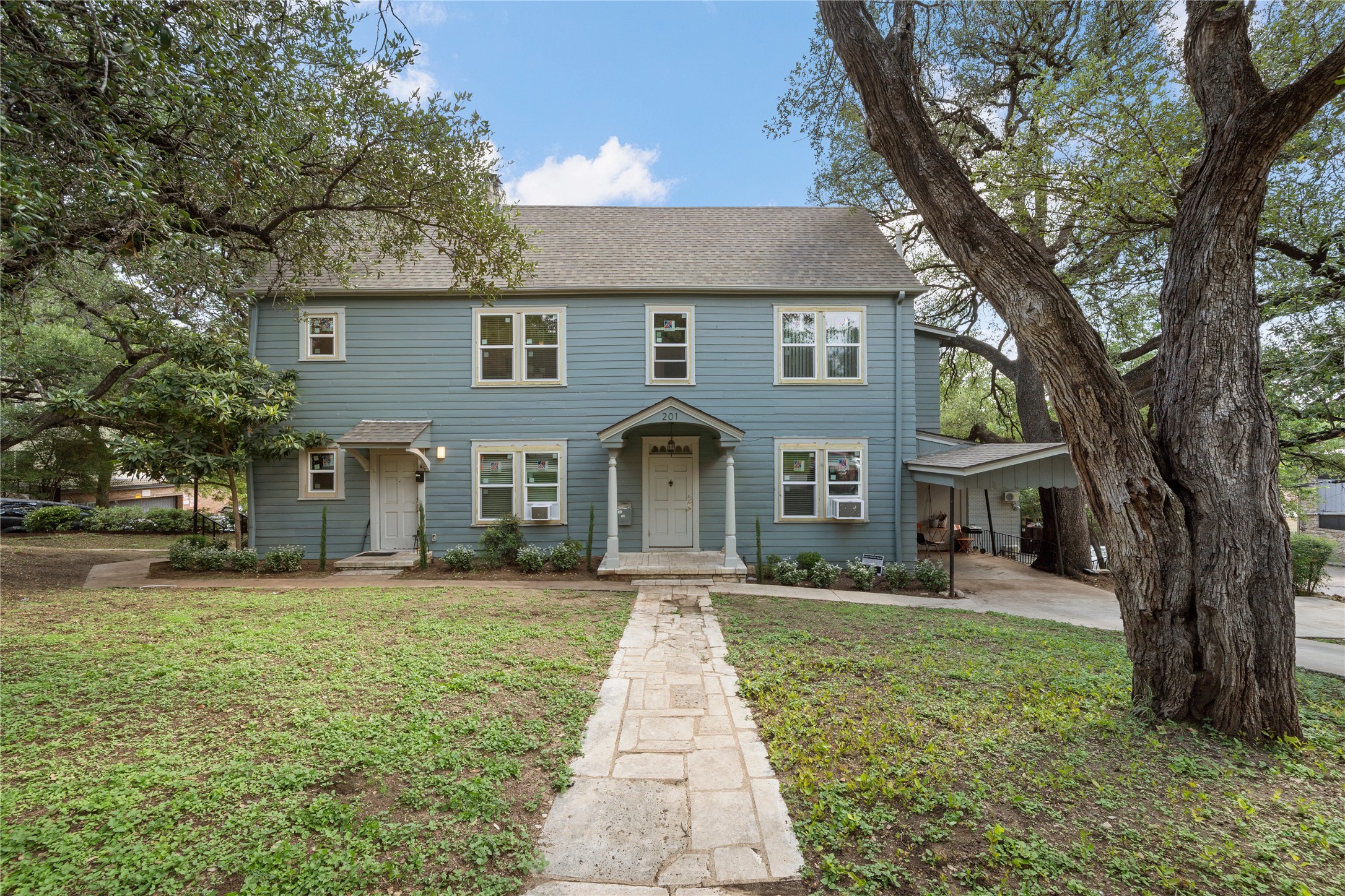 201 West 31st Street, Unit E Austin, TX 78705 - Photo 15 of 16 A classic facade with a charming stone pathway leading to a welcoming entrance, framed by mature shade trees.