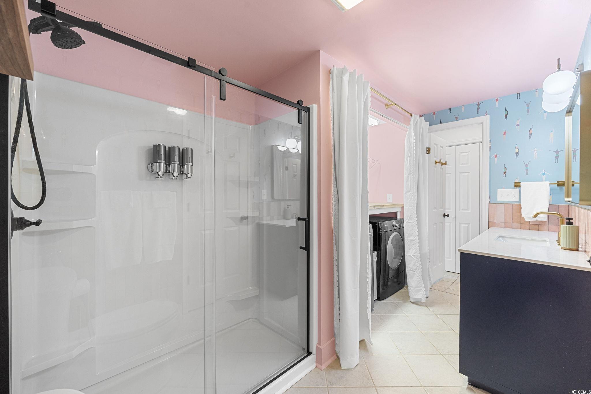 104 Ash Street North Myrtle Beach, SC 29582 - Photo 23 of 39 Bathroom with light tile patterned flooring, a shower stall, double vanity, wallpapered walls, and washing machine and clothes dryer