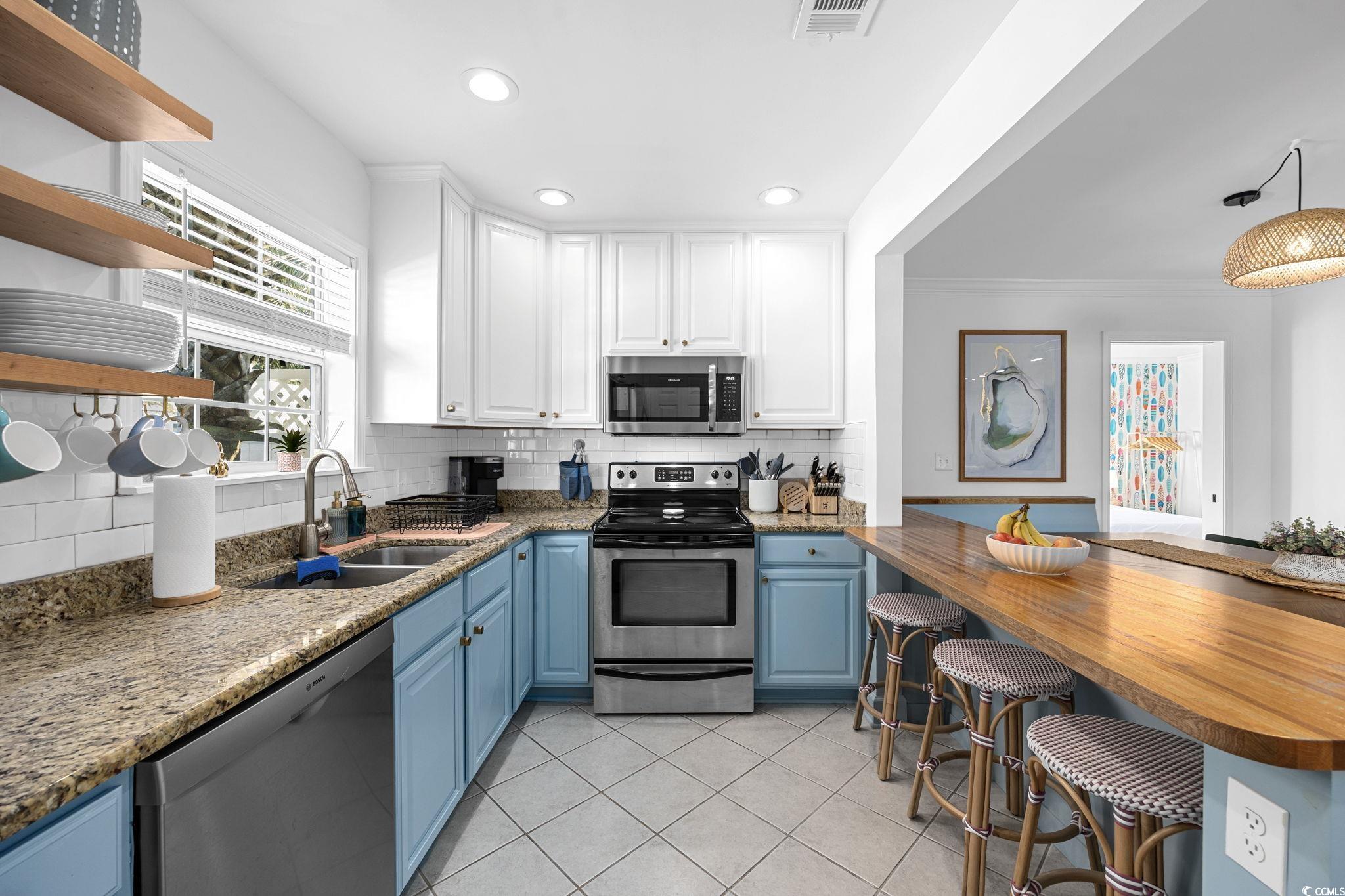 104 Ash Street North Myrtle Beach, SC 29582 - Photo 8 of 39 Kitchen with appliances with stainless steel finishes, backsplash, blue cabinetry, white cabinets, and open shelves