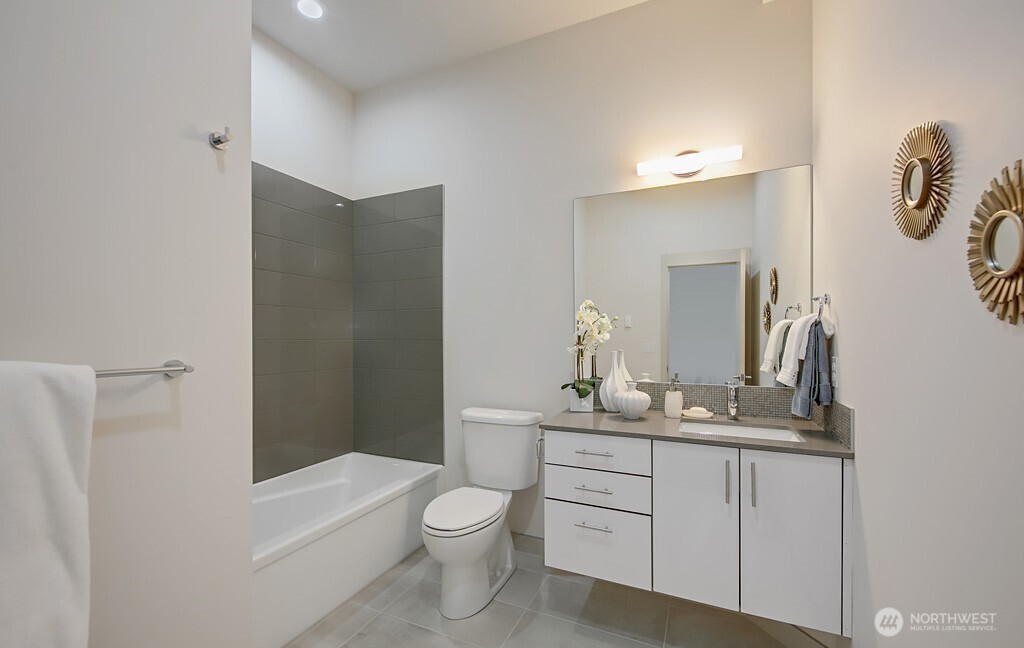 3516 Northeast 87th Street, Unit C Seattle, WA 98115 - Photo 6 of 18 a bathroom with a toilet a sink a tub and mirror