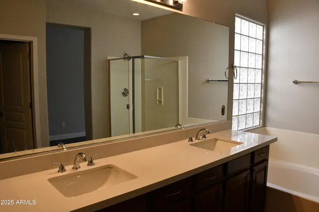 a bathroom with a sink double vanity granite tub shower and a mirror