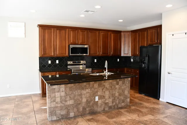 a kitchen with granite countertop a refrigerator a stove a microwave and island