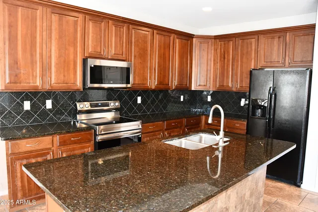 a kitchen with stainless steel appliances granite countertop a sink refrigerator and cabinets